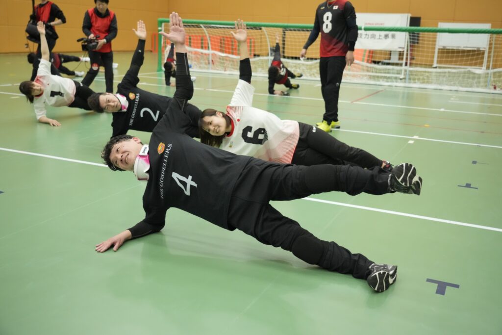 輪にになって基礎トレーニングをするゴスペラーズと女子の強化指定選手たち
